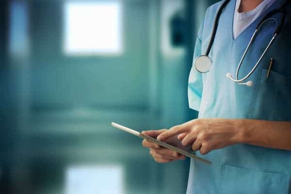 doctor in blue uniform with stethoscope working remotely via internet holding digital tablet case